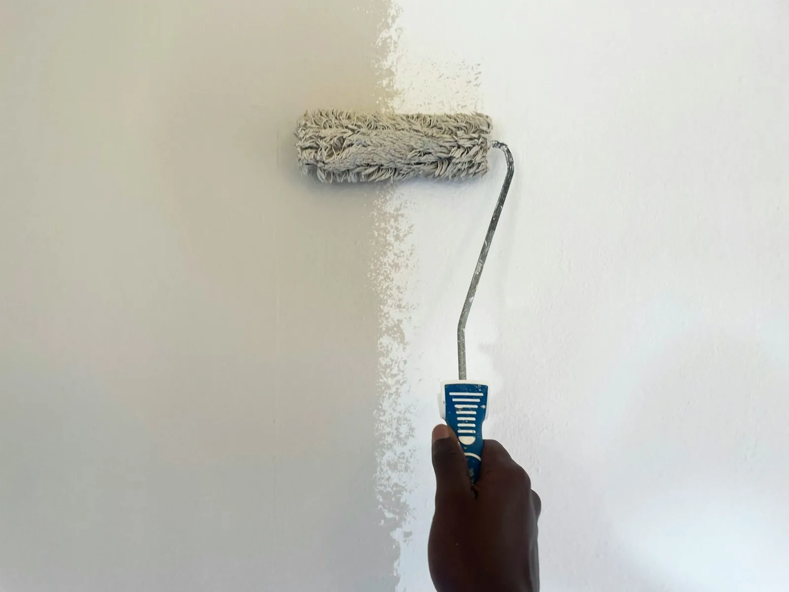 Paint roller finishing a wall touch-up after a drywall repair